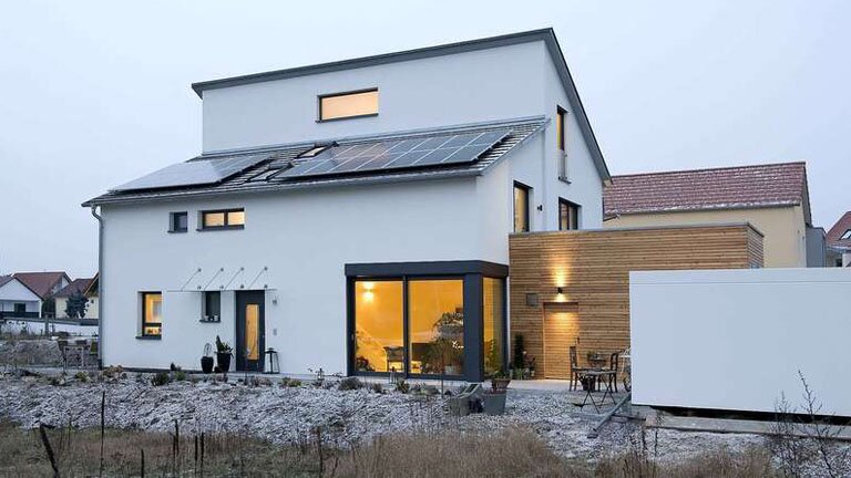 Haus, Sicht vom Garten auf Aussenfassade in das Innere des Hauses, Solarpanele auf dem Dach